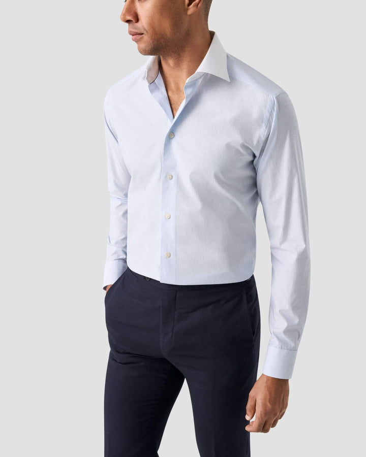 Chemise lignée bleu clair avec col blanc, coupe cintrée, élégante et moderne.
