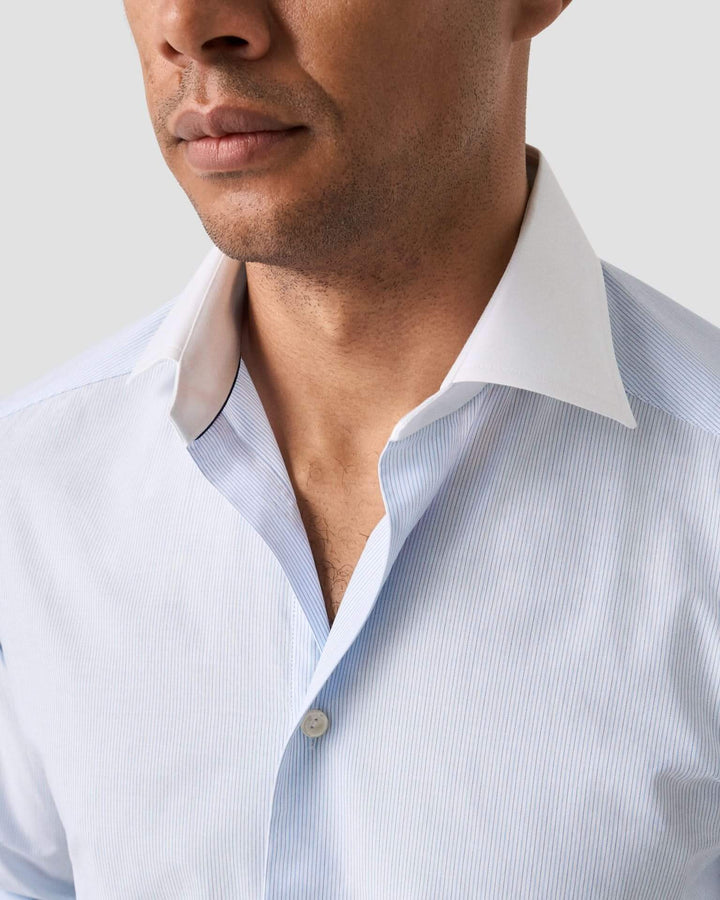 Chemise rayée bleu clair avec col blanc, coupe cintrée, style moderne et élégant.