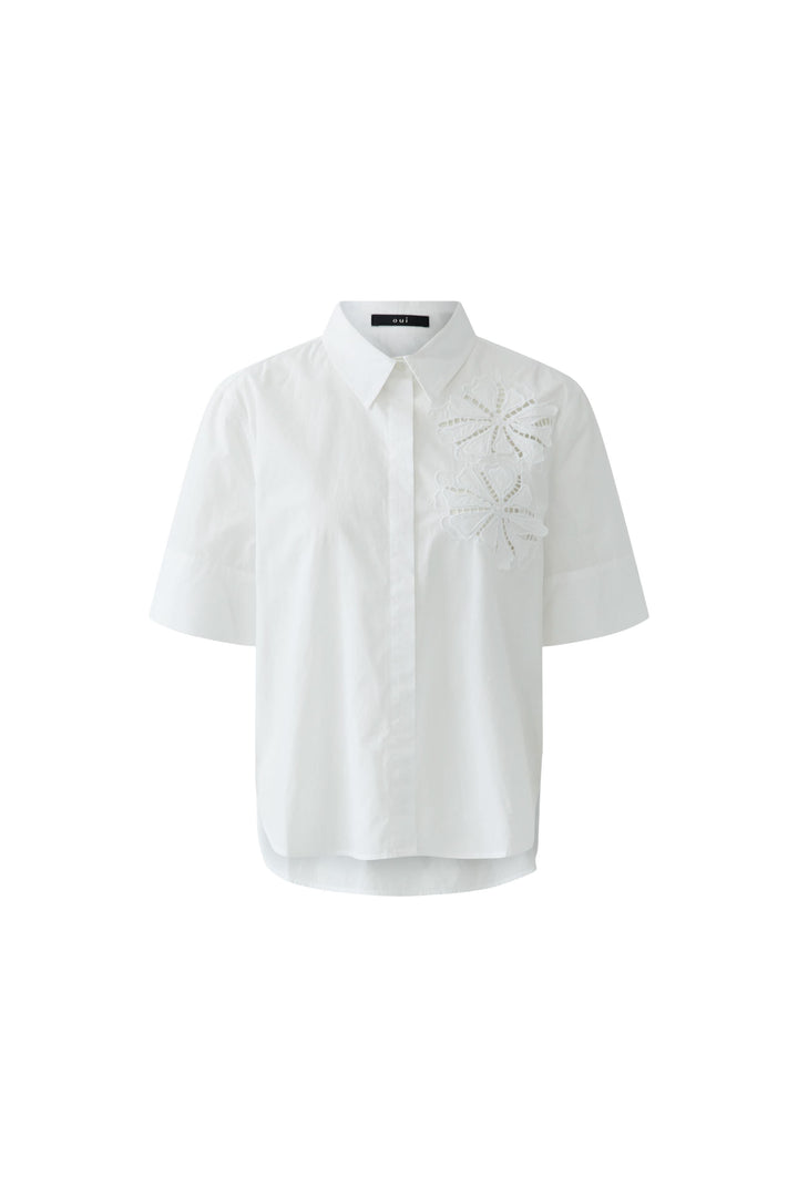Chemise à manches courtes avec broderie blanche délicate pour un look moderne et féminin.