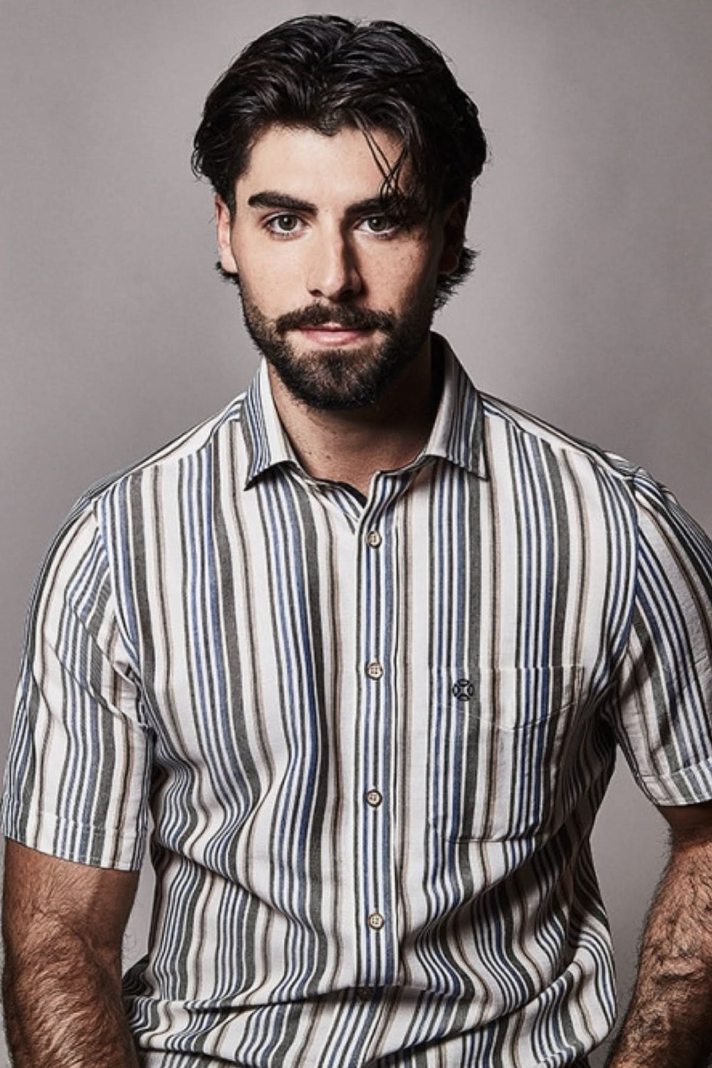 Homme portant une chemise à manches courtes à motif rayé avec col structuré et fermeture boutonnée.
