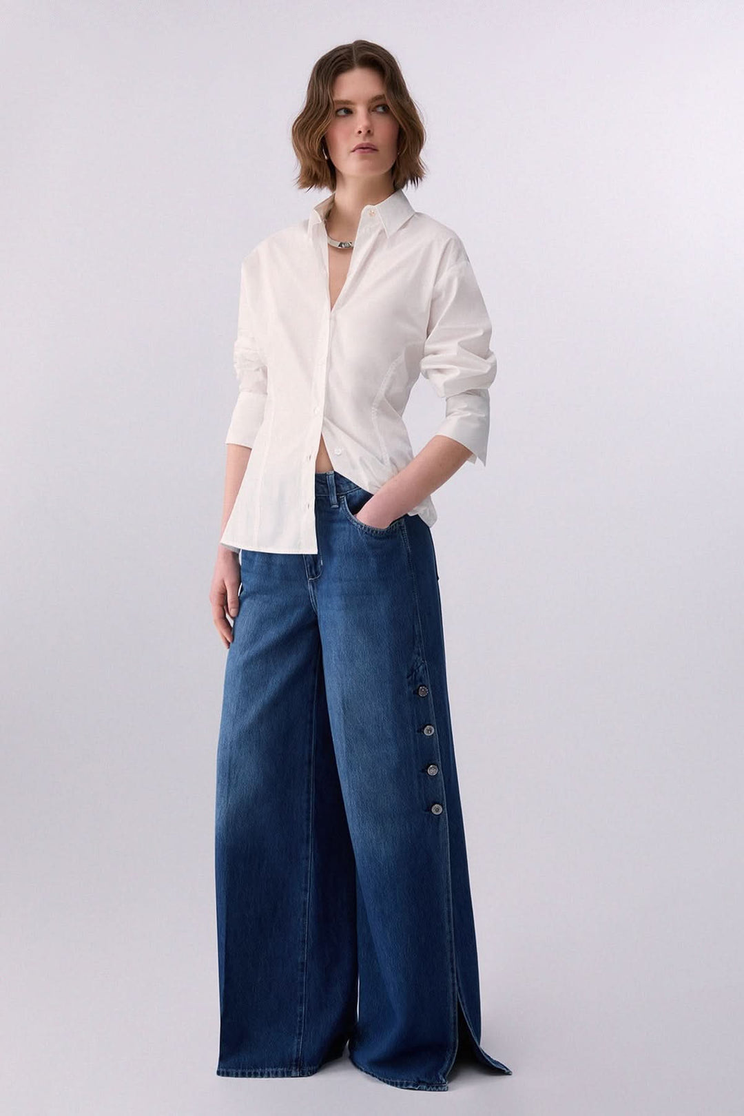 Femme portant une chemise à nouer au dos avec pantalon en jean, tenue moderne et féminine.