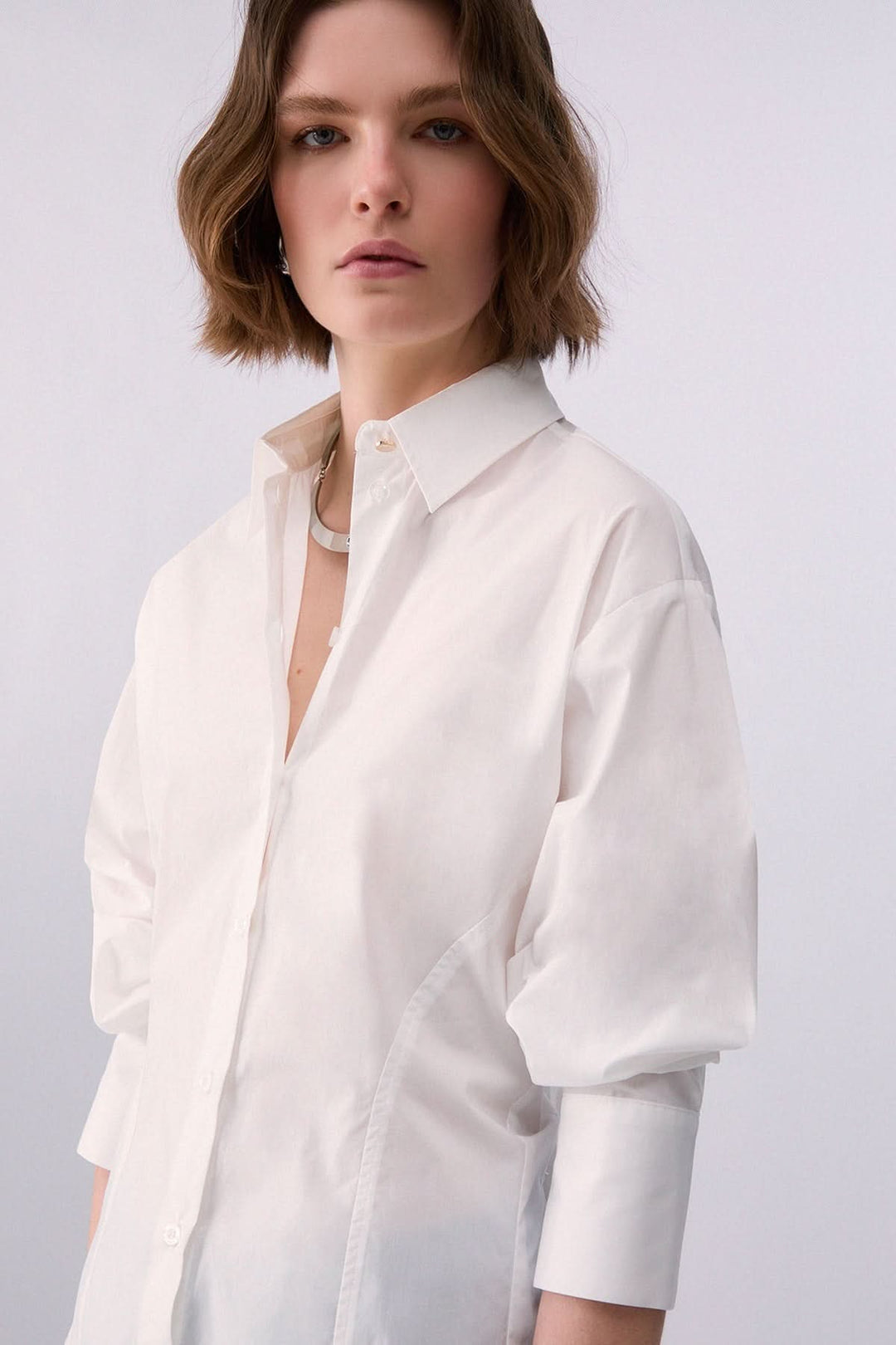 Femme portant une chemise à nouer au dos avec col classique, manches longues.