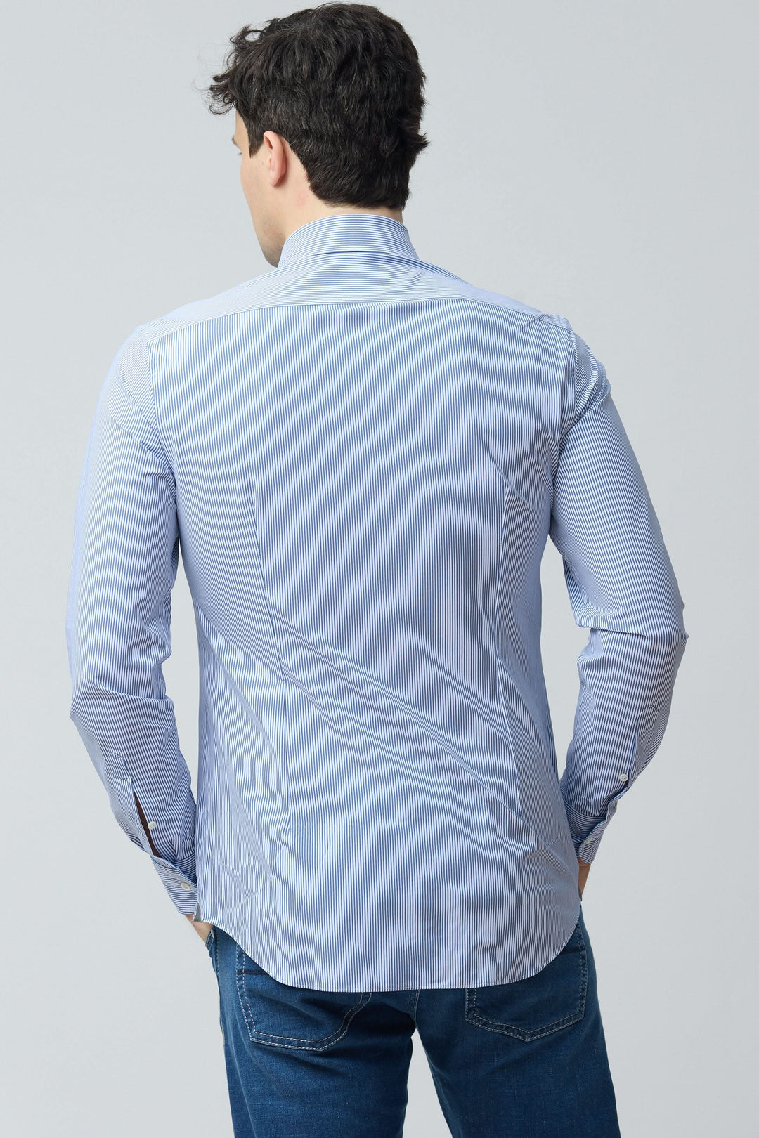 Homme portant une chemise à rayures fines modernes vue de dos, mettant en valeur la coupe ajustée et le tissu extensible pour un confort optimal.