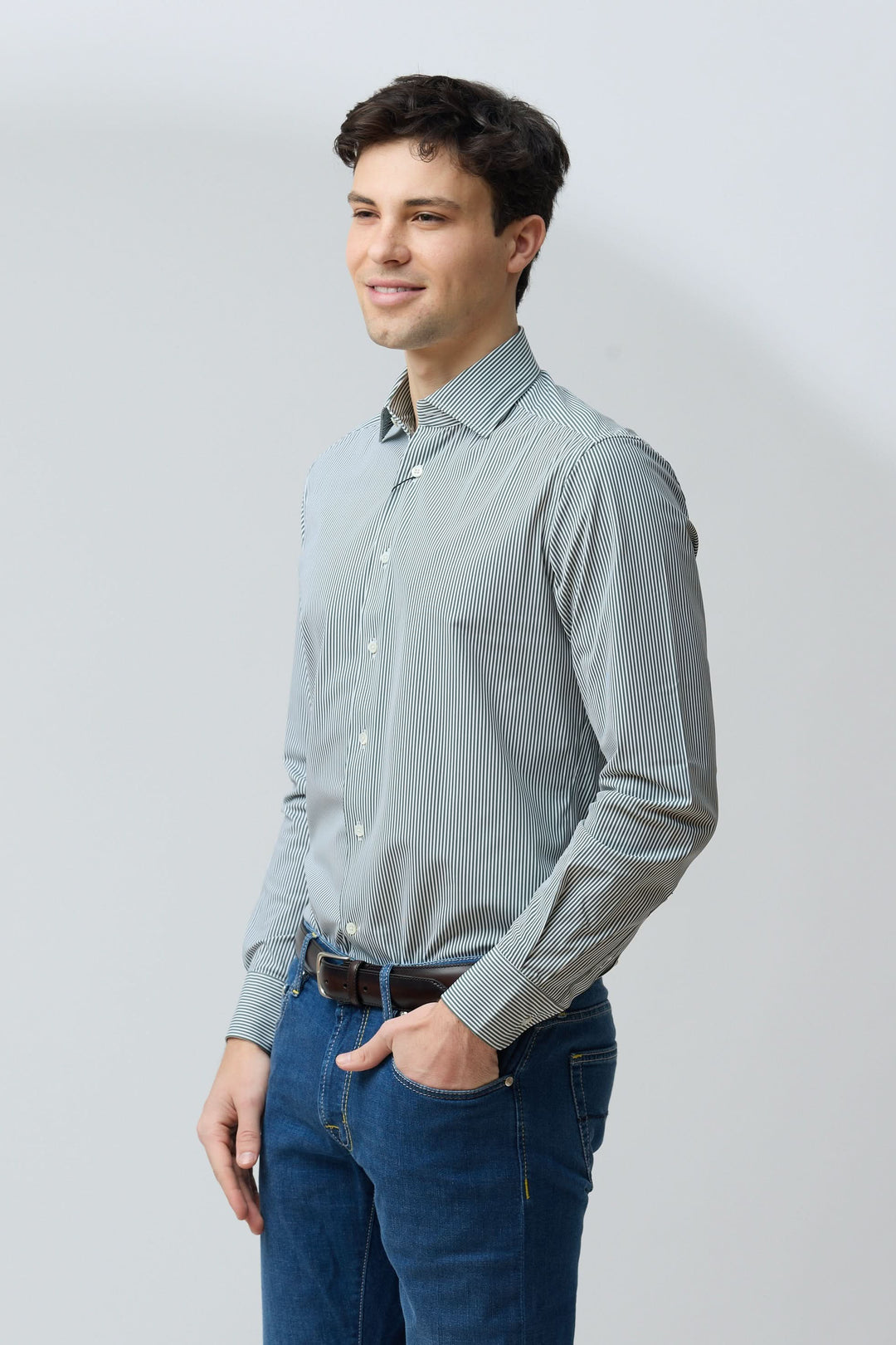 Homme portant une chemise à rayures vertes fines et jeans, coupe ajustée, idéale pour un look professionnel ou décontracté.