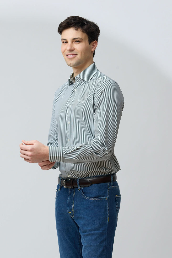 Homme portant une chemise à rayures vertes fines, coupe ajustée, avec jean, style moderne et confort, idéal pour différentes occasions.