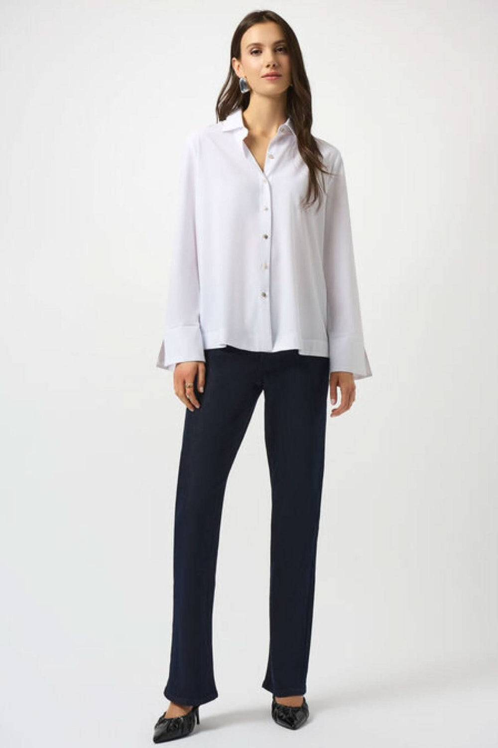 Chemisier classique blanc avec manches longues et boutons, porté avec un pantalon noir élégant.