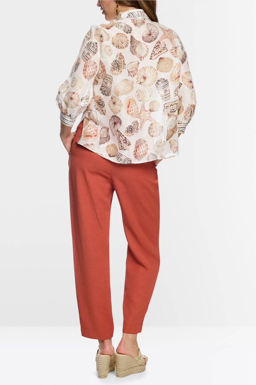 Chemisier fluide à imprimé coquillages porté avec un pantalon rouge, vue de dos, style décontracté et élégant pour toutes occasions.
