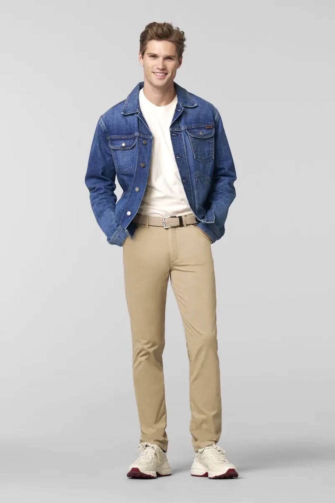 Homme portant un pantalon chino beige et une veste en jean, style décontracté chic, en tenue moderne.