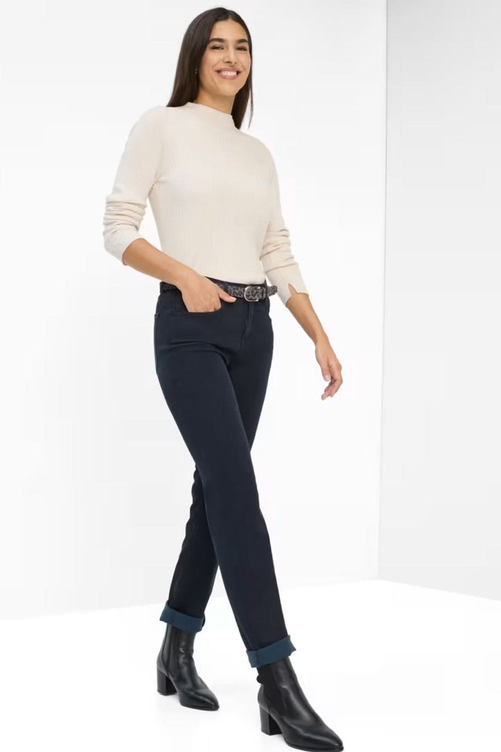 Femme portant un Chino de style Mary, tenue chic décontractée avec pull léger et bottines noires, coupe ajustée, couleur camel élégante.