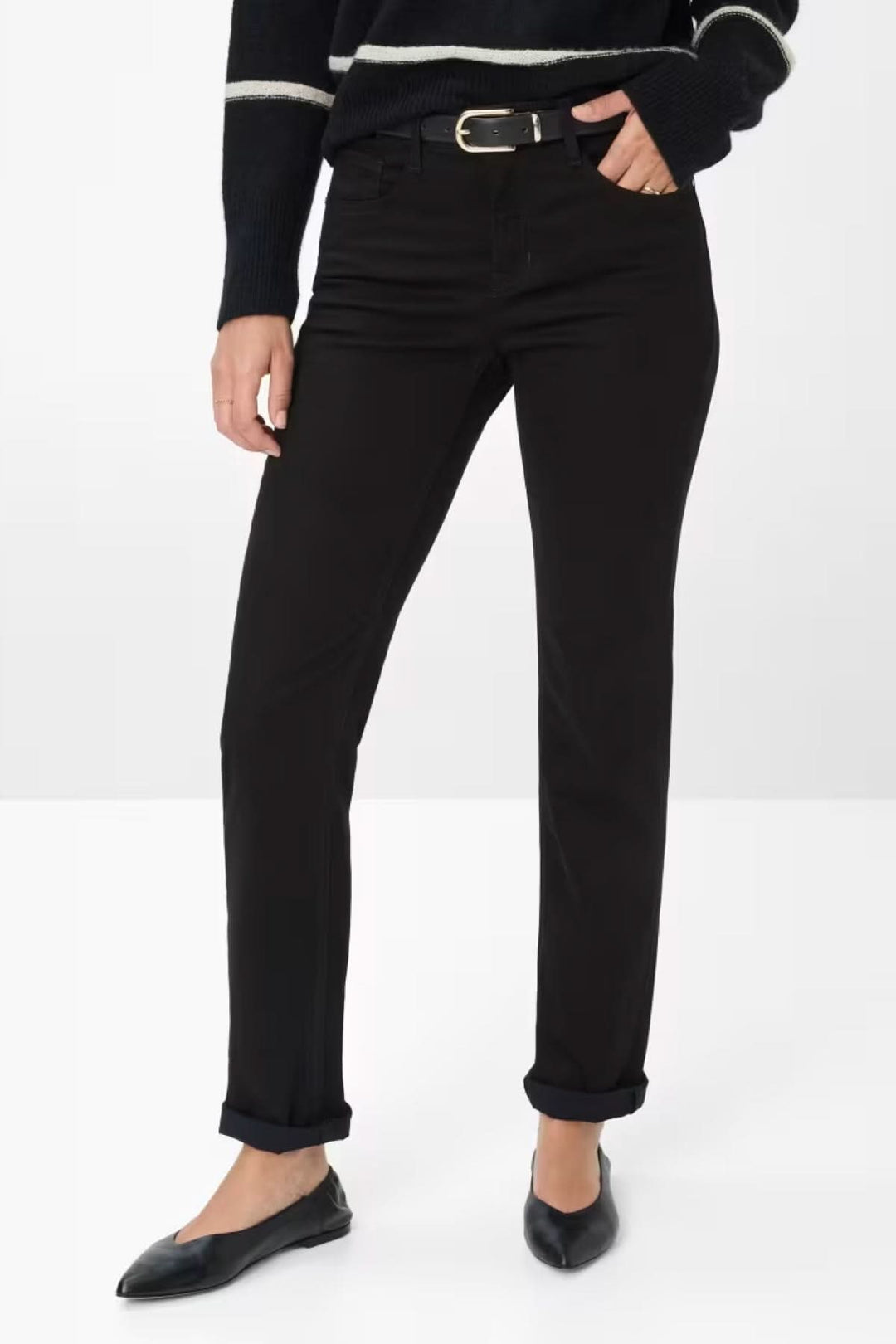 Femme portant un Chino de style Mary noir ajusté avec ceinture, associé à un pull rayé pour un look casual chic élégant.
