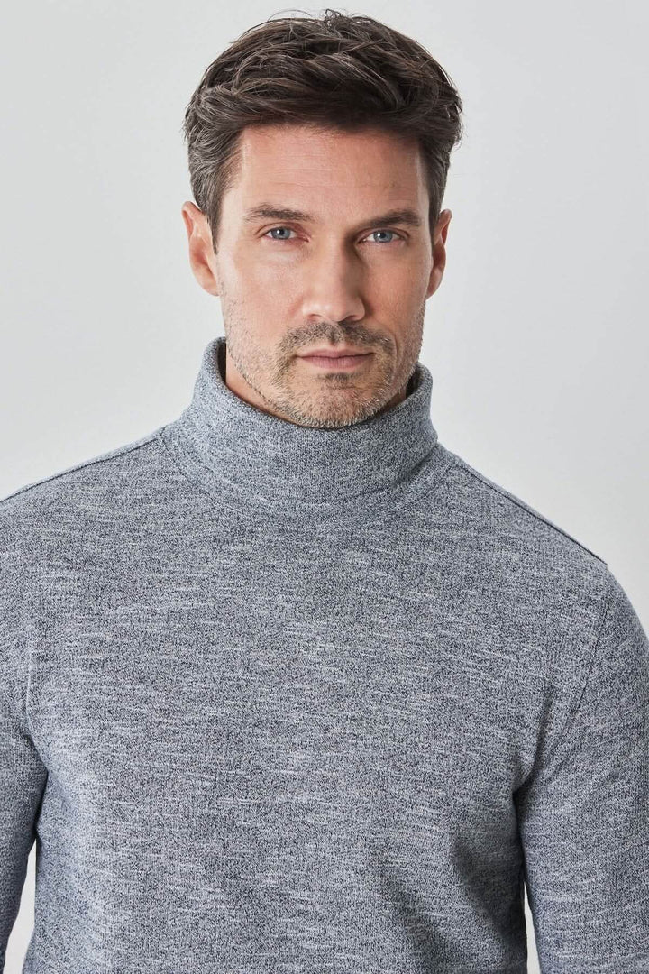 Homme portant un col roulé gris en coton, un vêtement confortable avec un look élégant et raffiné.