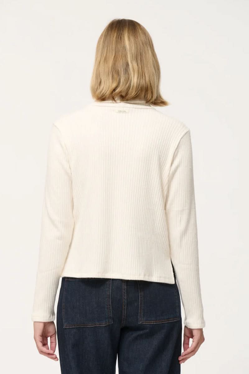 Dos d'un col roulé côtelé en jersey blanc avec manches longues et petites fentes sur les côtés.