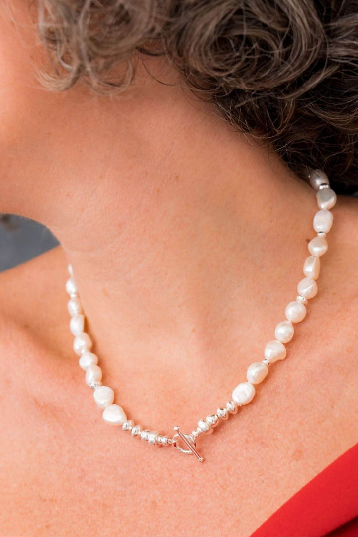 Collier élégant en perles d'eau douce, porté avec un fermoir en T pour un style sophistiqué.
