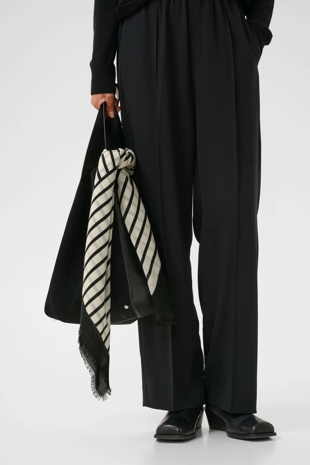 Foulard rayé moderne en noir et blanc, porté avec des pantalons noirs, ajoutant une touche élégante à la tenue.