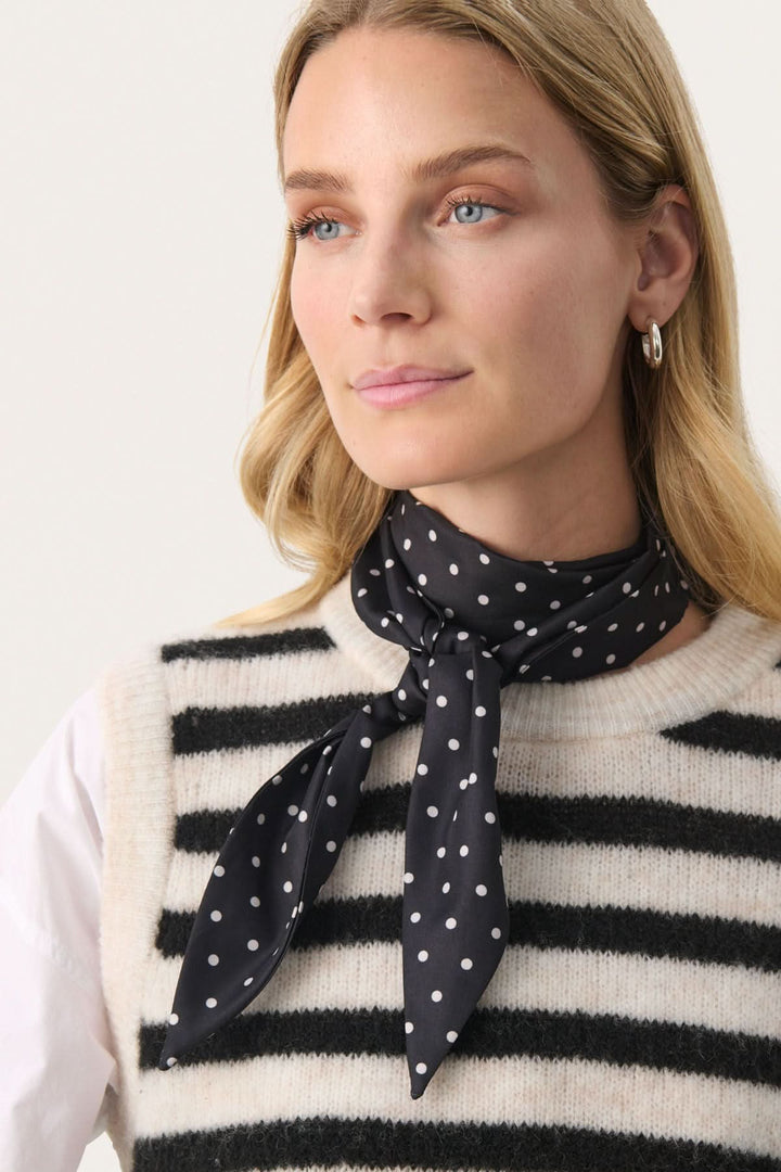 Foulard Lupa à pois porté par une femme, ajoutant une touche féminine à une tenue décontractée.