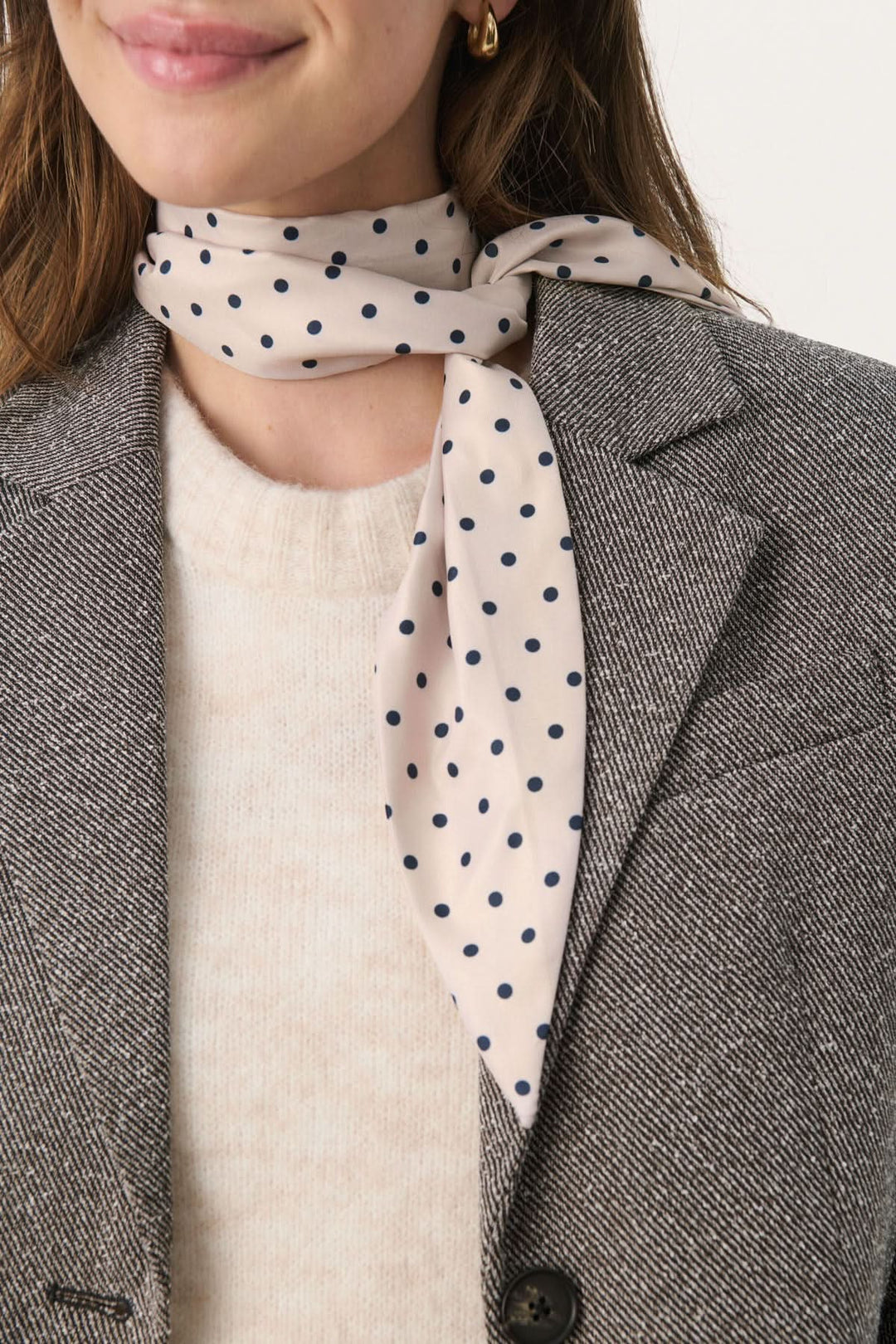 Foulard Lupa à pois porté avec élégance, ajoutant une touche féminine à une tenue chic.