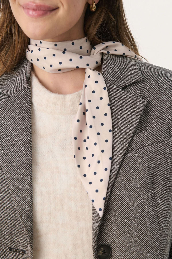 Foulard Lupa à pois porté avec élégance, ajoutant une touche féminine à une tenue chic.