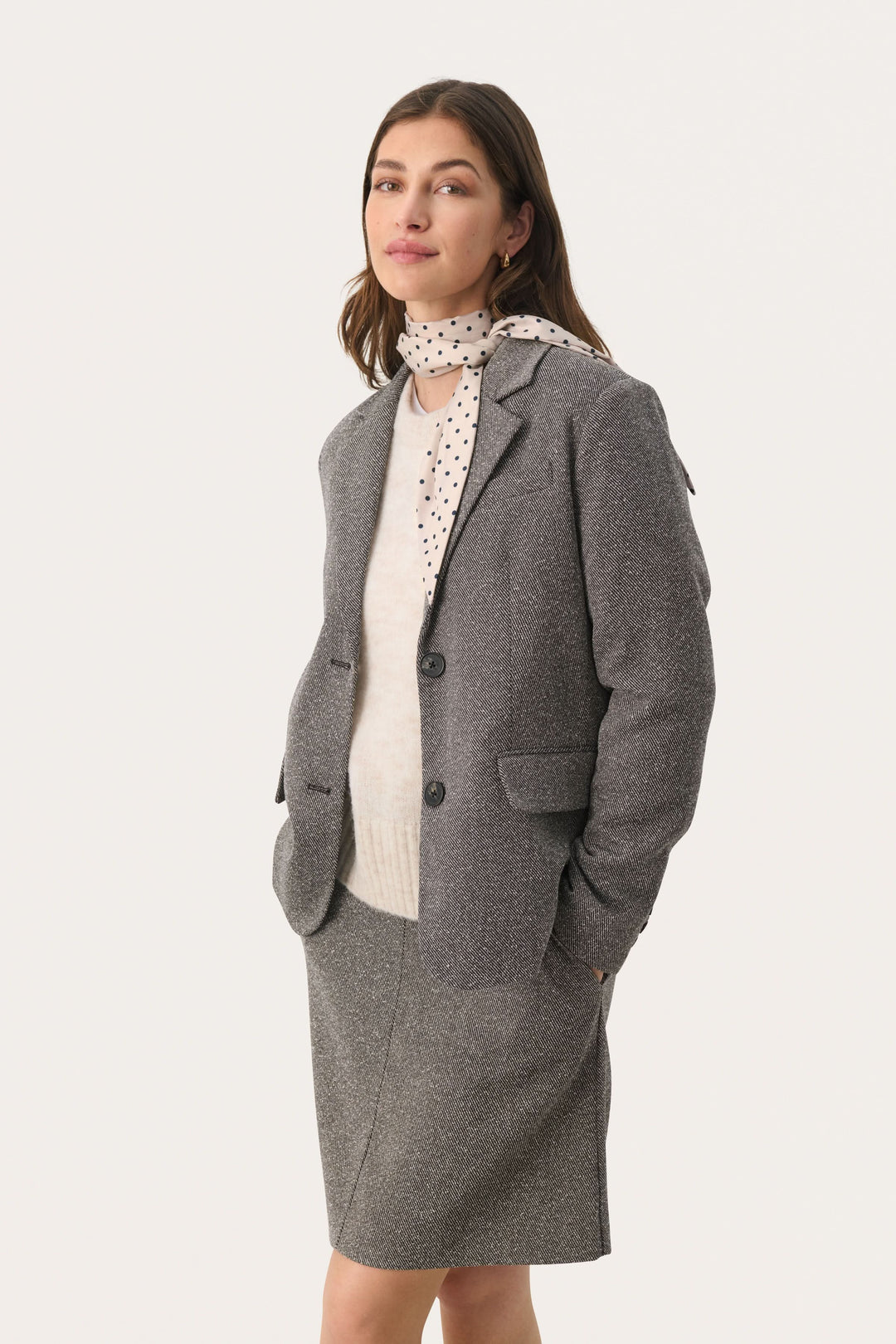 Foulard Lupa avec pois, associé à un blazer gris, offrant un look féminin et élégant.