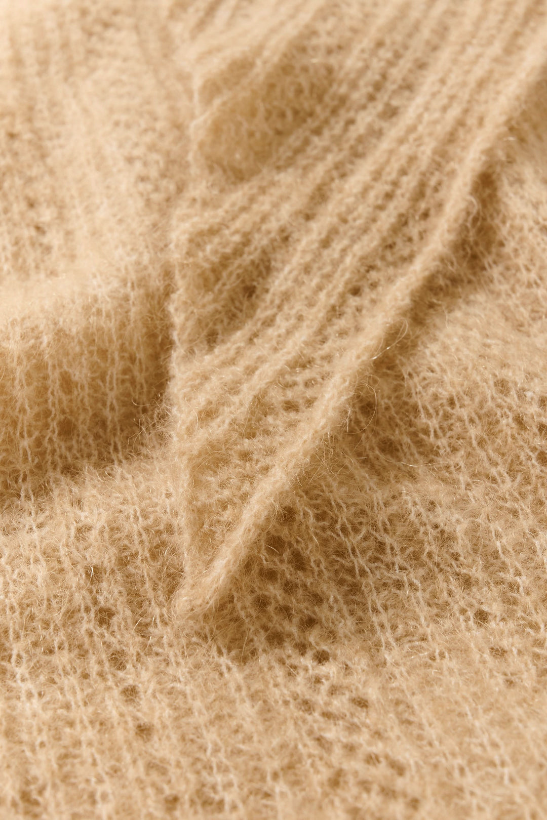 Détail du foulard Sizze en tricot léger couleur beige, montrant une texture douce et effilée.