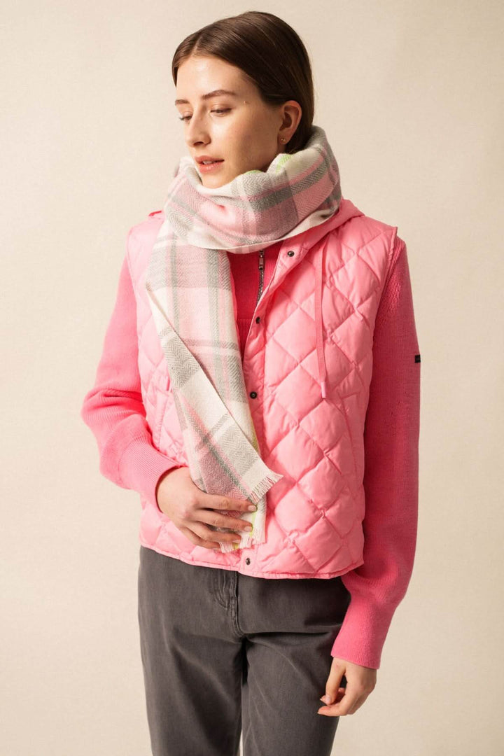Foulard à carreaux doux et enveloppant en tissu moelleux porté sur un pull rose, décris moi le produit en français, accessoire d'hiver.