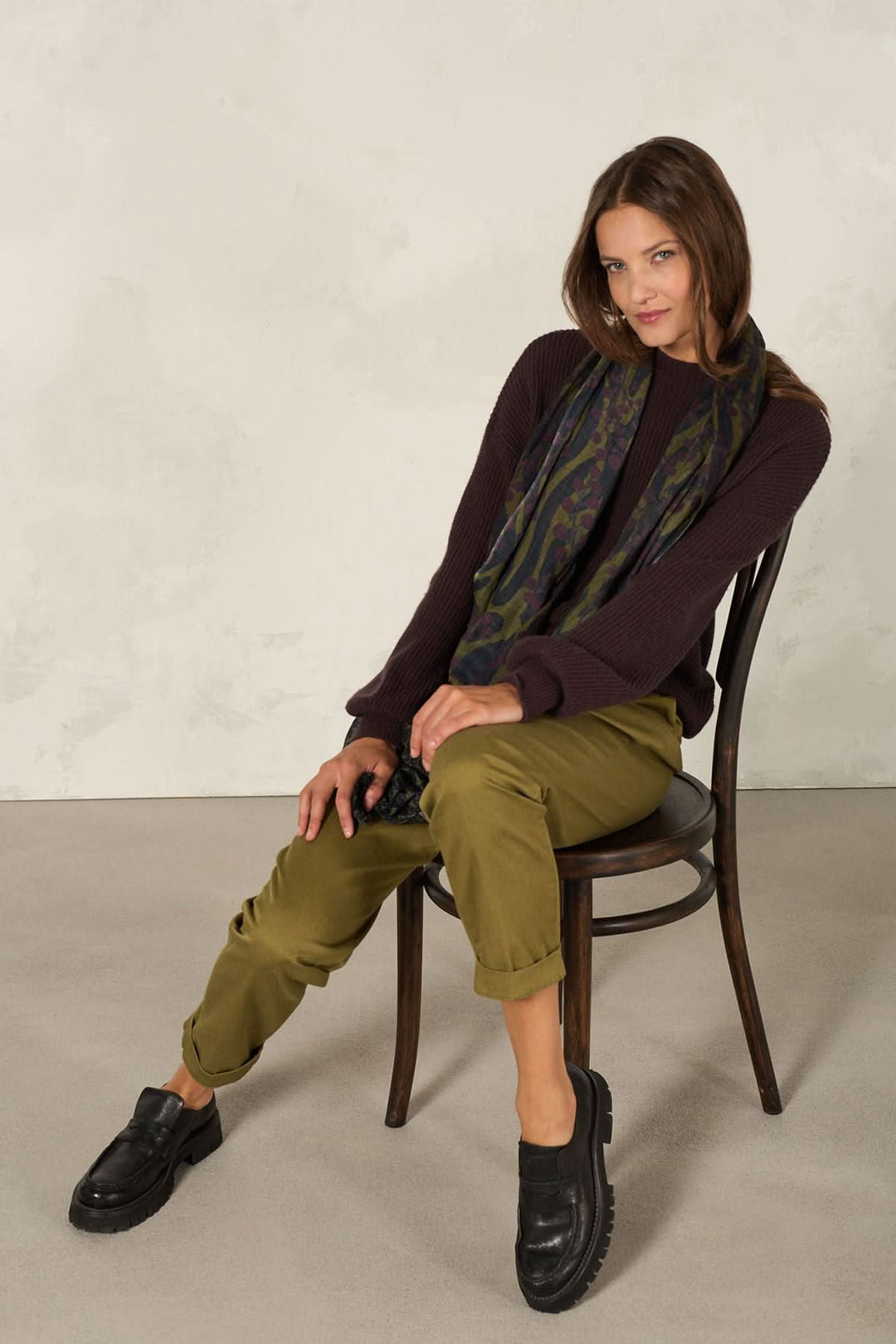 Foulard décoratif porté par une femme assise sur une chaise, style élégant et artistique.