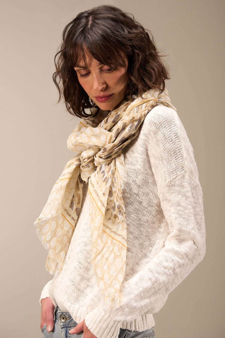 Écharpe imprimée en coton bio, portée élégamment sur un pull, ajoutant sophistication et style.