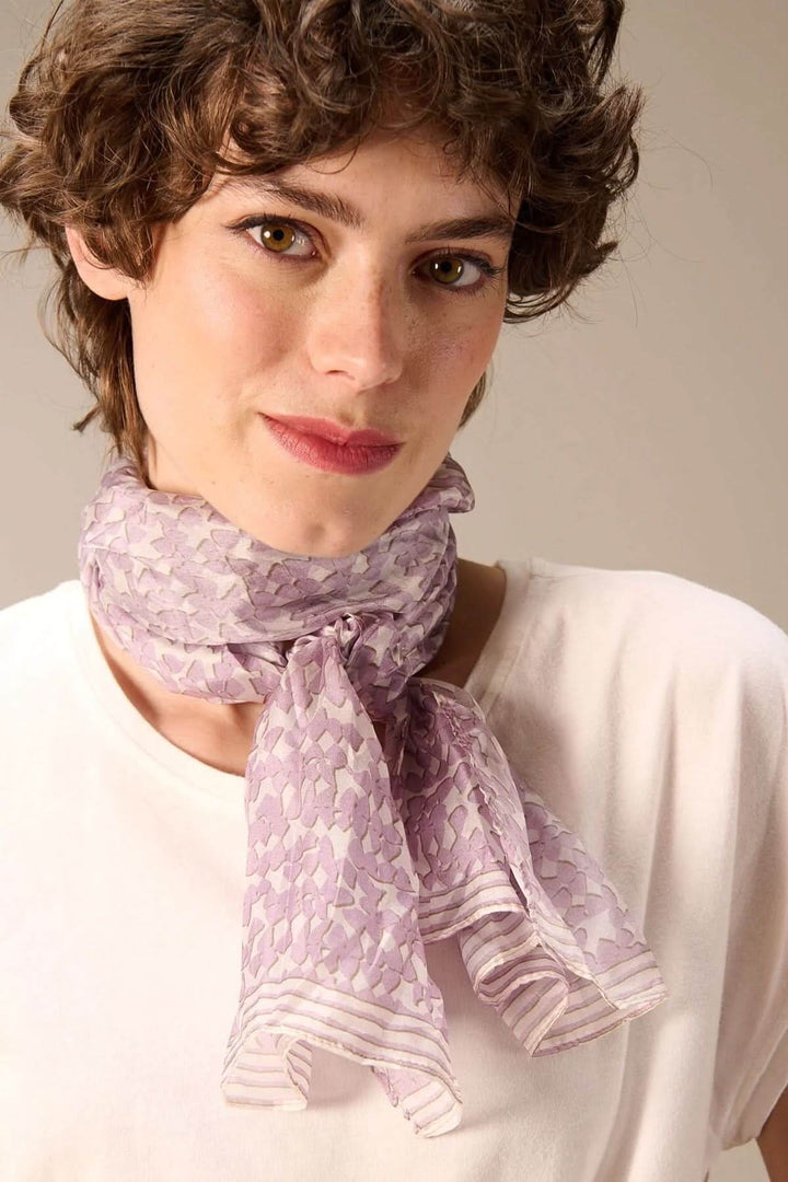 Femme portant un foulard léger imprimé autour du cou, accessoire moderne et élégant en tissu fluide et imprimé délicat.