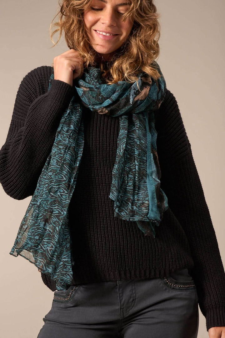 Foulard paréo en soie avec imprimé bleu et noir porté avec un pull noir.