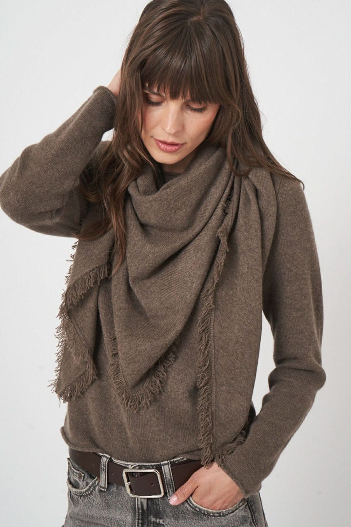 Foulard triangulaire en maille douce avec franges, porté de manière élégante et décontractée par une femme.