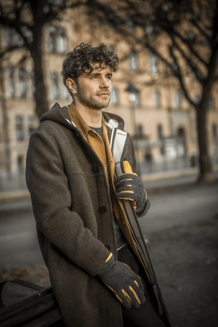 Homme portant des gants de cuir Noah avec un manteau élégant, profitant d'une journée en plein air.