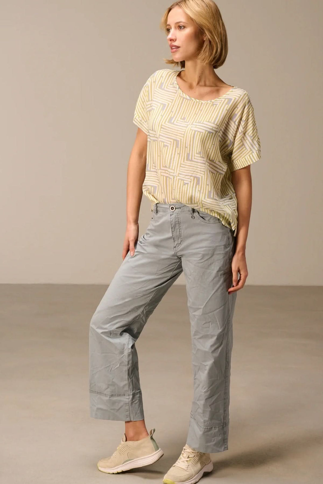 Femme portant un haut fluide imprimé manches courtes avec pantalon, montrant un look moderne et confortable.