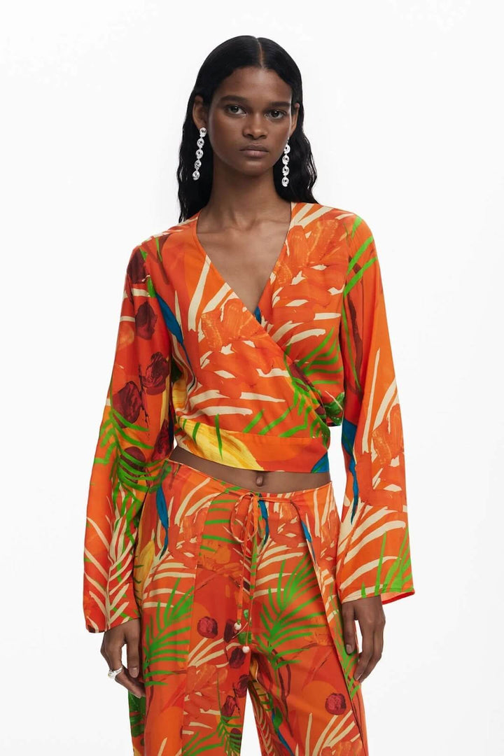 Haut à manches longues orange en tissu tropical léger avec encolure croisée et manches évasées.