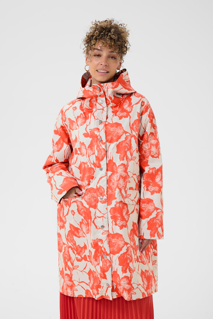 Imperméable Olif à motif floral, coupe droite et longueur sous le genou, porté pour un style moderne et fonctionnel.