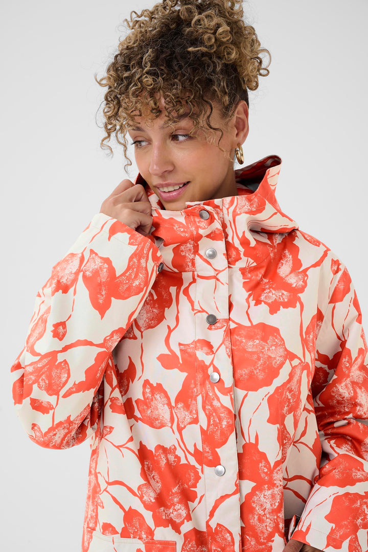 Femme portant un Imperméable Olif à motif floral expressif, coupe droite, idéale pour les journées pluvieuses.