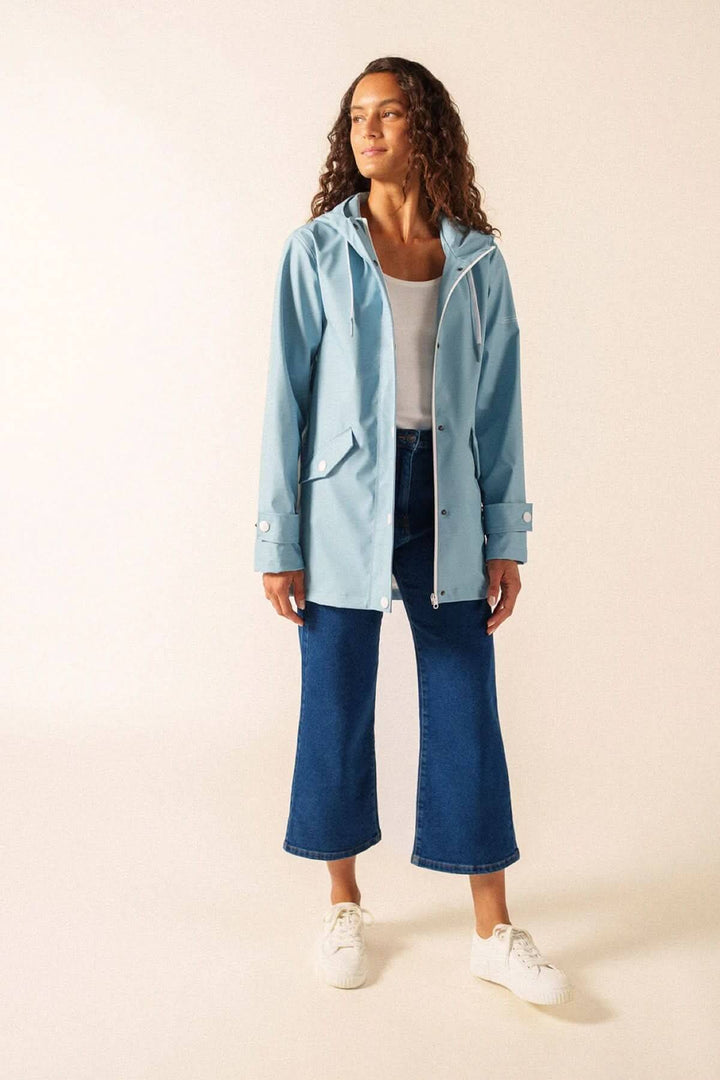 Femme portant un Imperméable STE GAIA bleu clair moderne et waterproof, idéal pour la ville ou la mer.