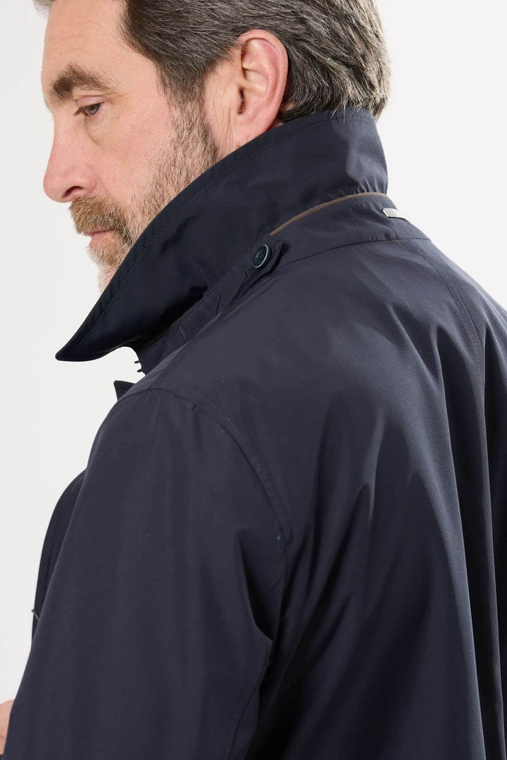 Homme portant un imperméable à col structuré, idéal pour les jours de pluie.