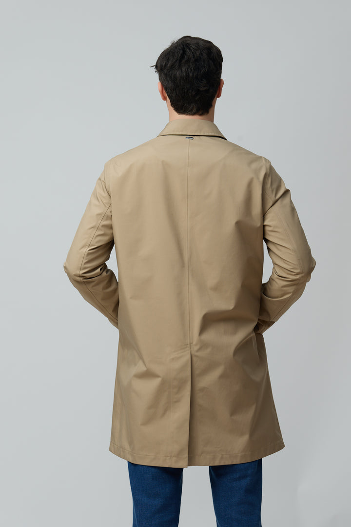 Homme portant un Imperméable en microfibre technique beige, coupe classique, dos visible. Finitions soignées, allure moderne et épurée.