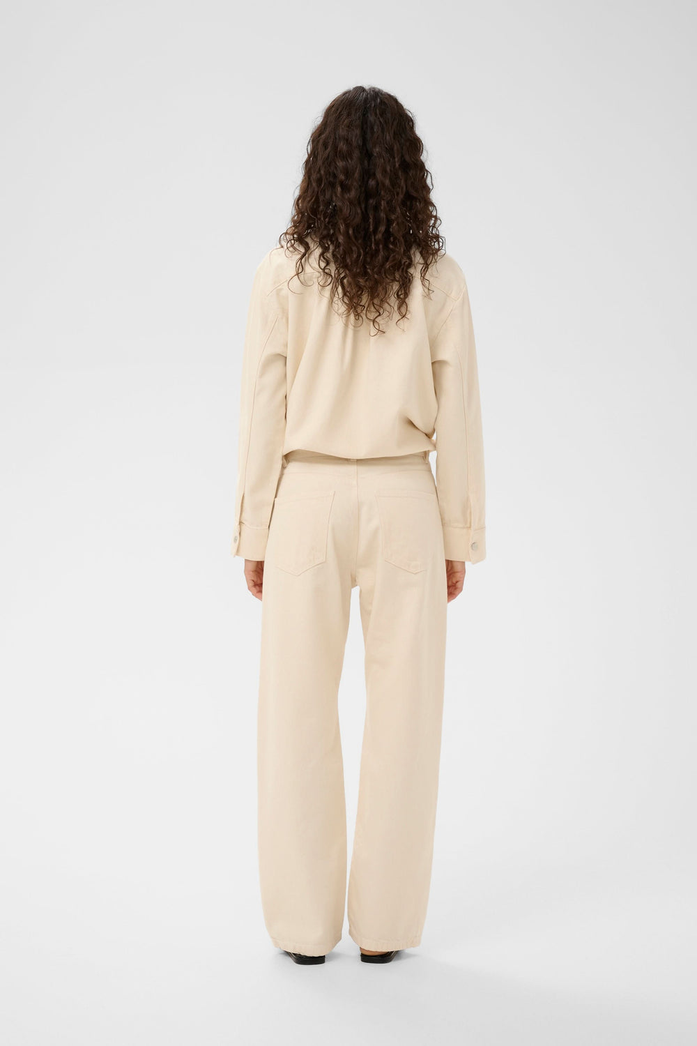 Vue arrière d'une femme portant un pantalon beige classique.