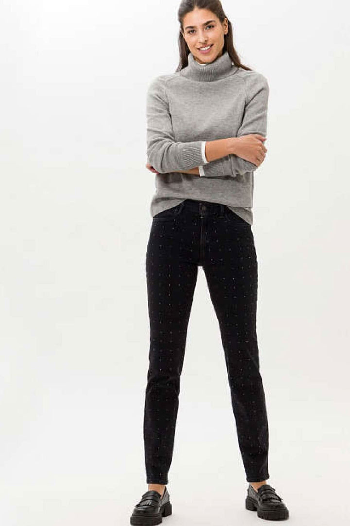 Femme portant un jean Shakira skinny avec strass, associé à un pull gris, style tendance.