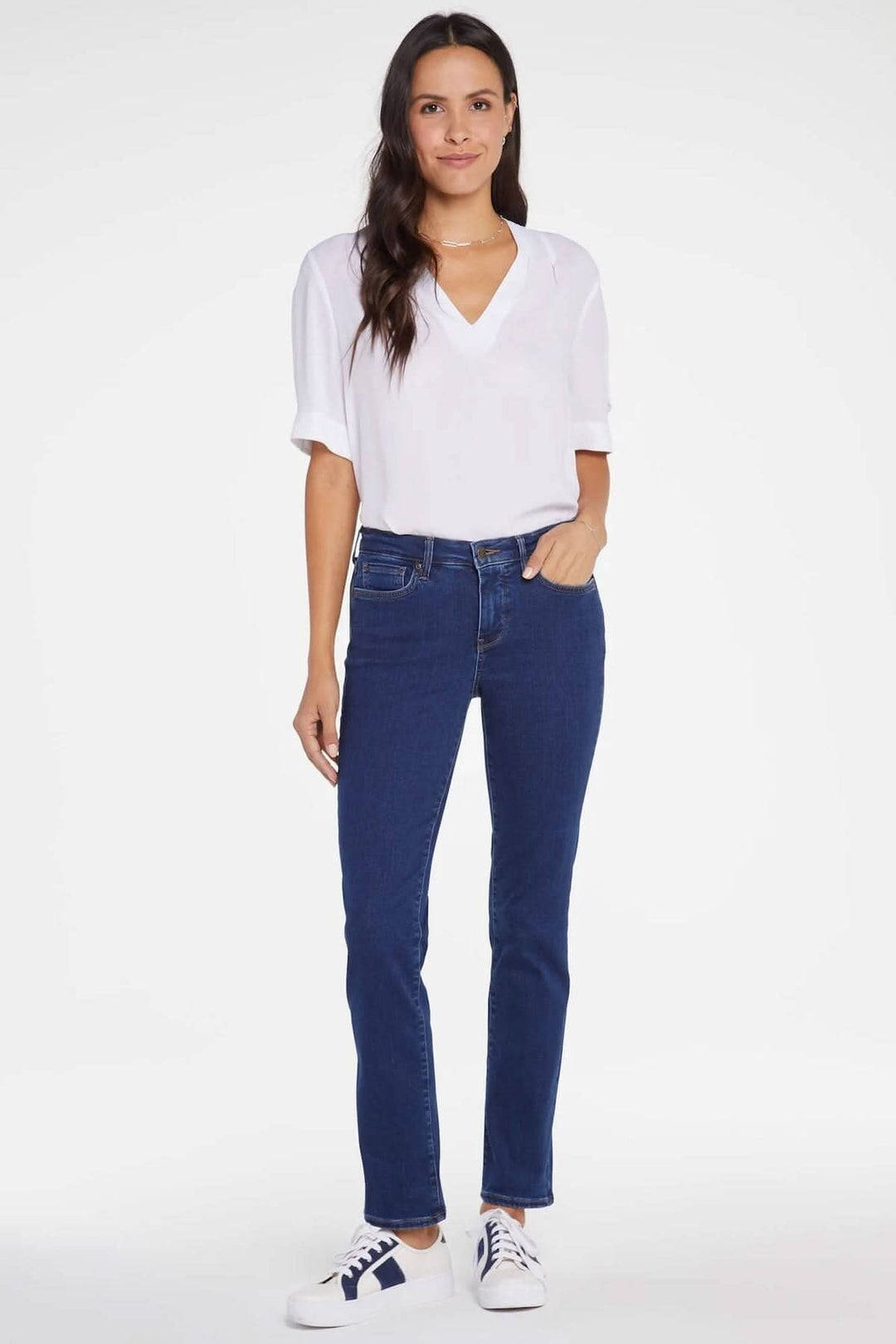 Femme portant le jean Sheri, coupe ajustée, avec un haut blanc et des baskets, style décontracté.