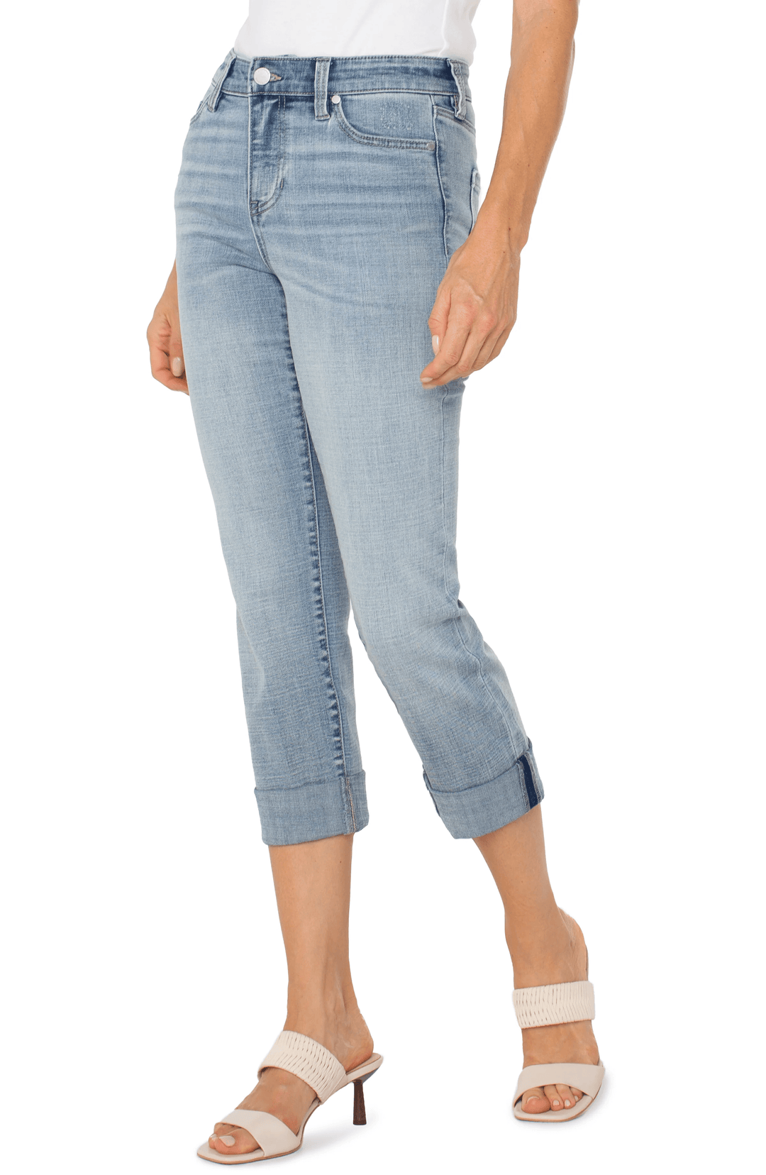 Jean capri à revers en denim délavé, coupe ajustée et taille mi-haute, porté avec des sandales élégantes.