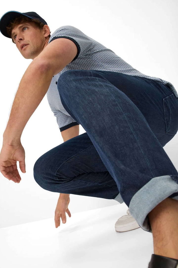 Homme en jean cinq poches moderne, style décontracté avec capuche, posé en crouche.