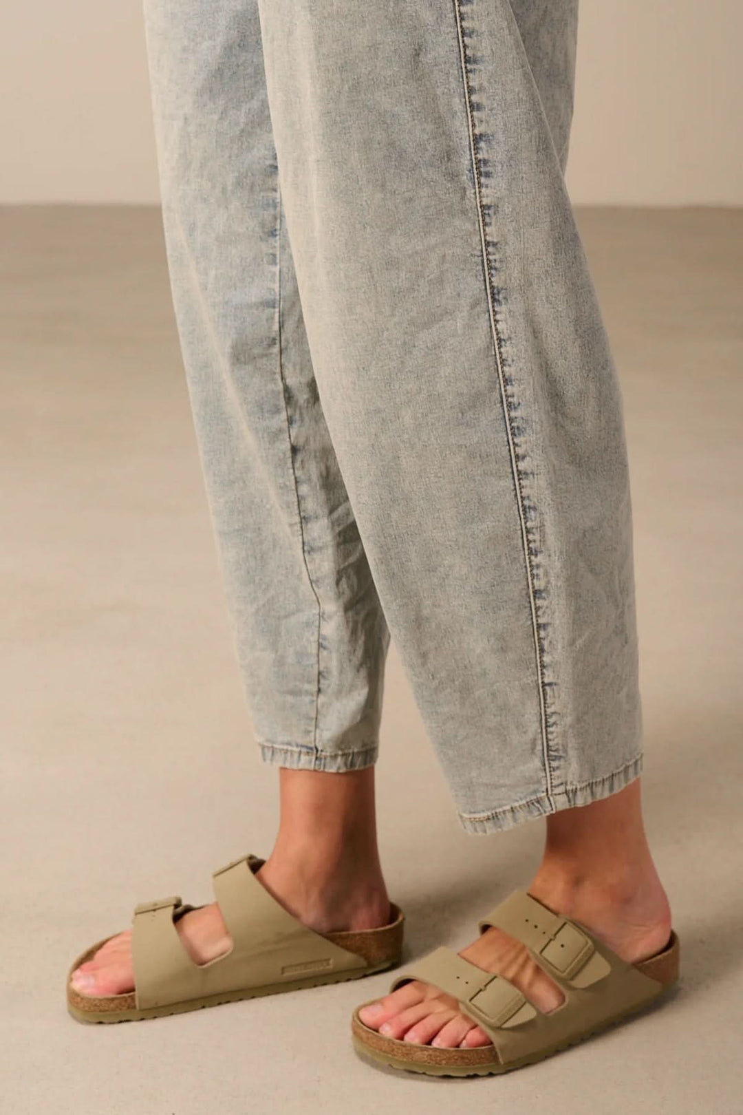 Jean à coupe décontractée en denim souple, idéal pour un style casual, avec sandales beiges pour plus de confort.