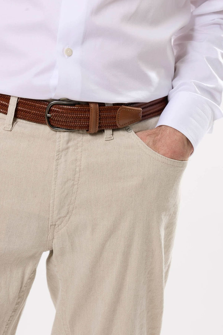 Homme portant un pantalon clair et une chemise blanche, avec une ceinture marron en cuir, style décontracté.