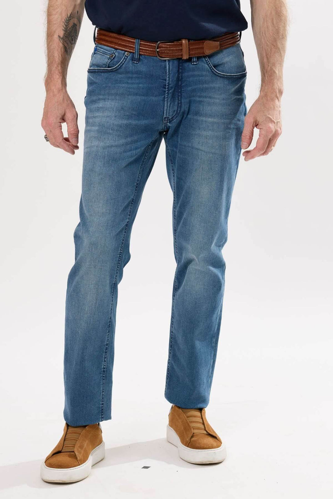 Jean coupe droite en denim légèrement extensible avec effet usé, porté avec un t-shirt et une ceinture en cuir.