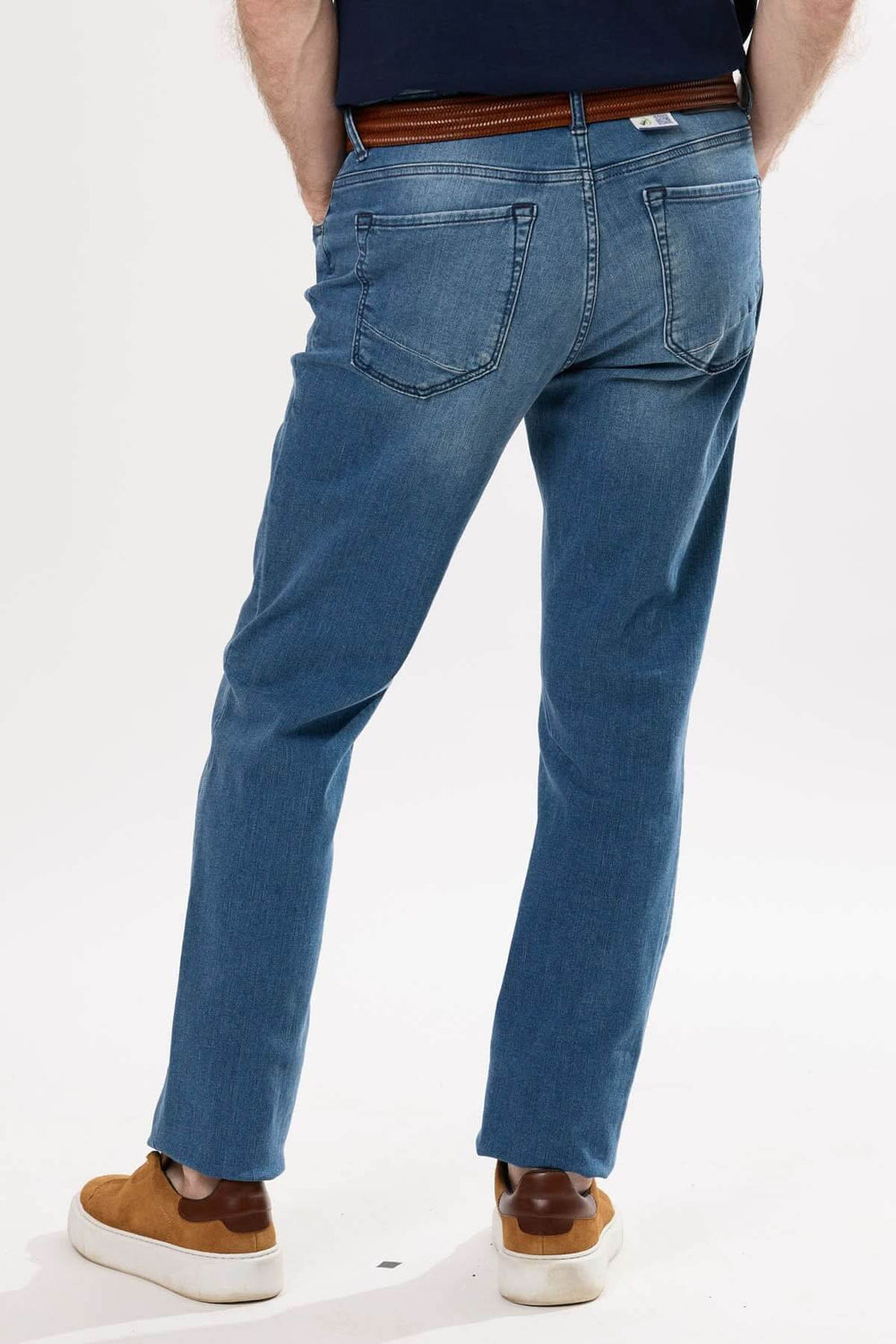 Jean coupe droite pour homme, effet usé léger, style décontracté, porté avec ceinture et chaussures claires.