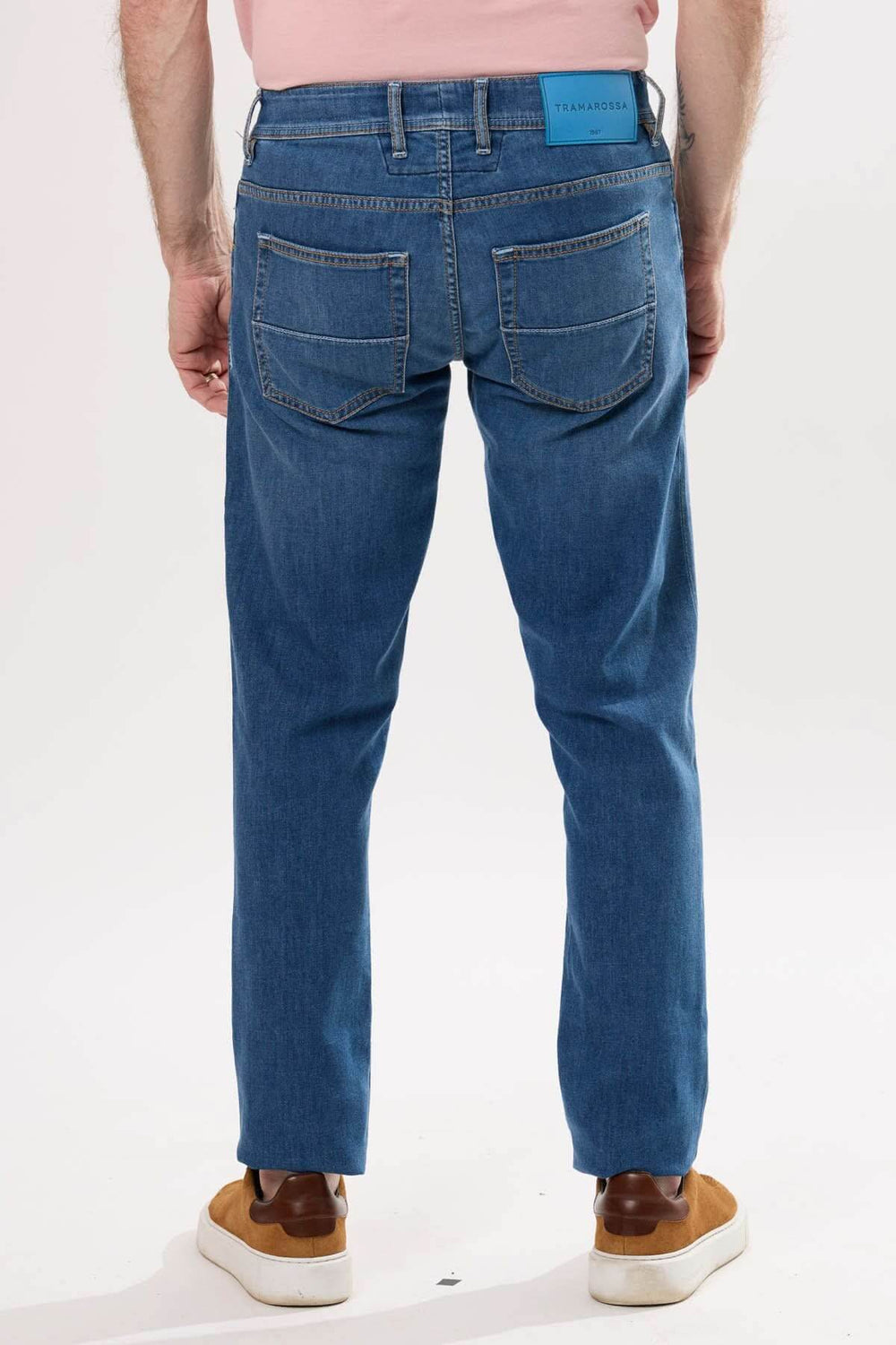 Jean coupe droite en toile extensible, finition délavée, porté en arrière, mode décontractée masculine.