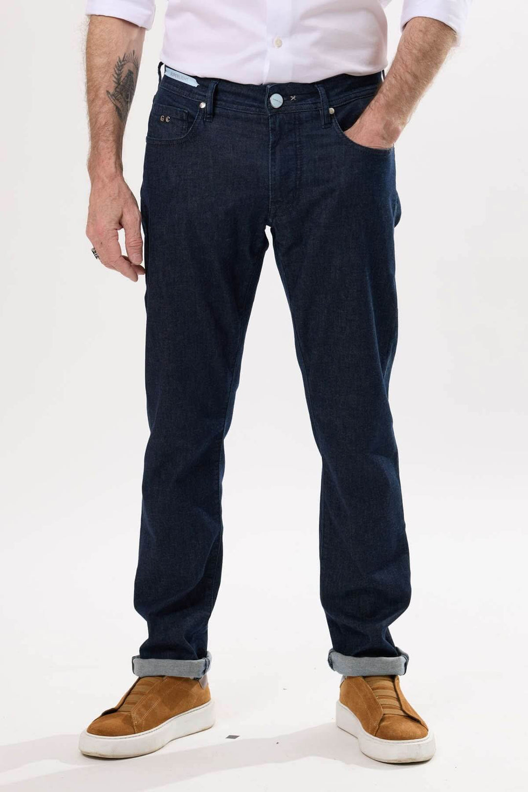 Jean coupe droite brut porté avec une chemise blanche et des baskets, style moderne et polyvalent.