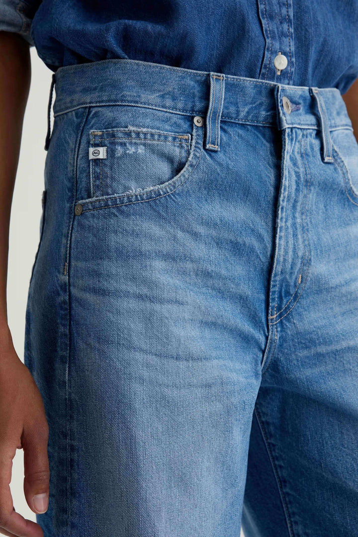 Jean droit à jambe large en denim bleu avec taille haute, offrant une allure moderne et décontractée pour un style minimaliste.