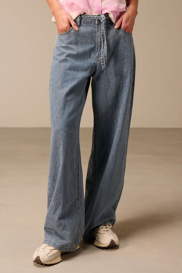 Jean à jambe large avec ceinture à nouer, denim souple et ample, mode décontractée.